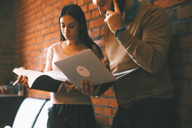 Two business professionals collaborating in a modern brick-walled office.